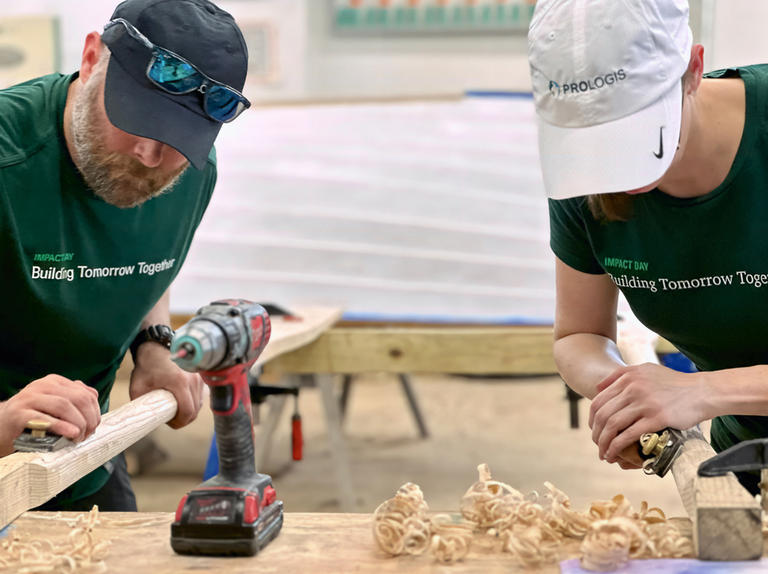 Two Prologis employees sanding wood at an IMPACT Day project