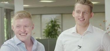 Two men in an office smiling at the camera