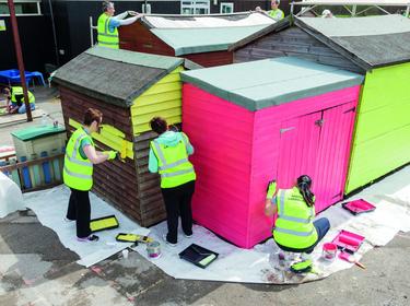 Three Prologis team members painting a building