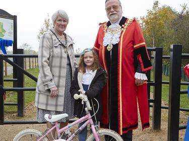 A woman and child in front of a bicycle with a man dressed in uniform