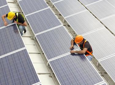 2 workers on top of a roof with solar panels